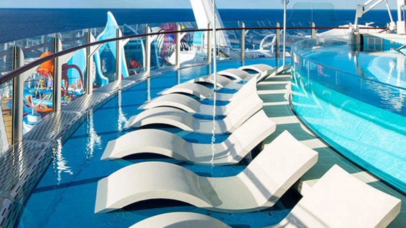 Cruise ship pool deck featuring in-water loungers and a relaxing outdoor pool