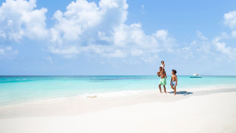 Papa et enfants marchant sur la plage de Nassau