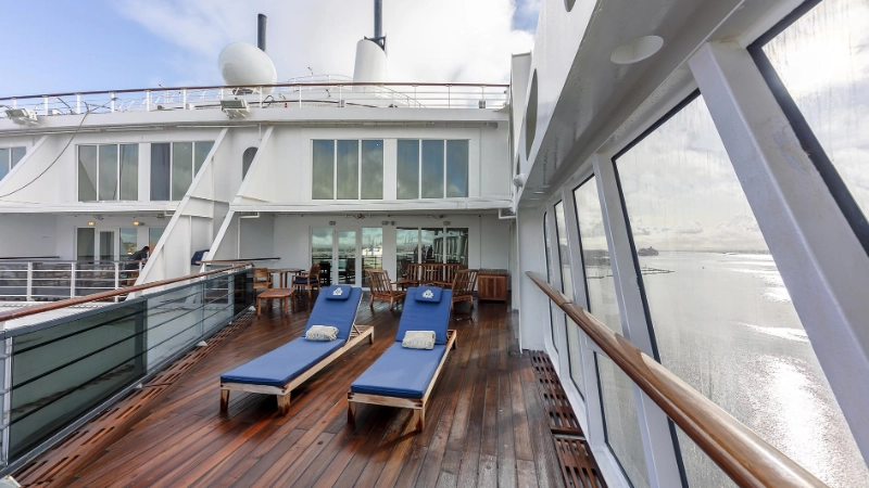 Wooden lounge chairs on a quiet outdoor deck of a cunard cruise ship overlooking the ocean