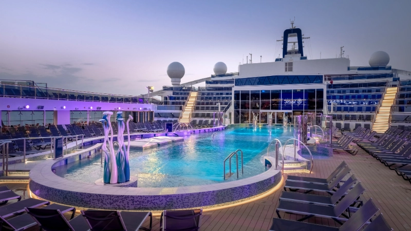 Outdoor swimming pool and lounge deck on MSC Cruises World Europa cruise ship illuminated at dusk