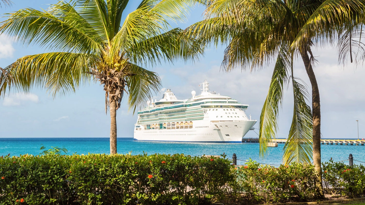 Navire de croisière blanc amarré dans les eaux turquoise des Caraïbes, entouré de palmiers par une journée ensoleillée