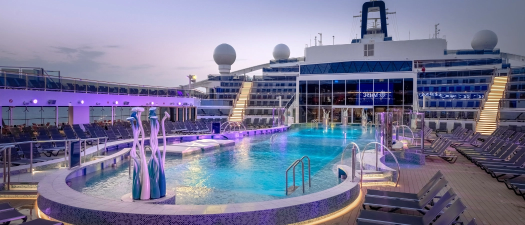 Outdoor swimming pool and lounge deck on MSC Cruises World Europa cruise ship illuminated at dusk