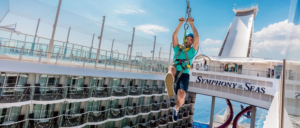 Guest riding a zip line above the deck of Royal Caribbean's Symphony of the Seas cruise ship