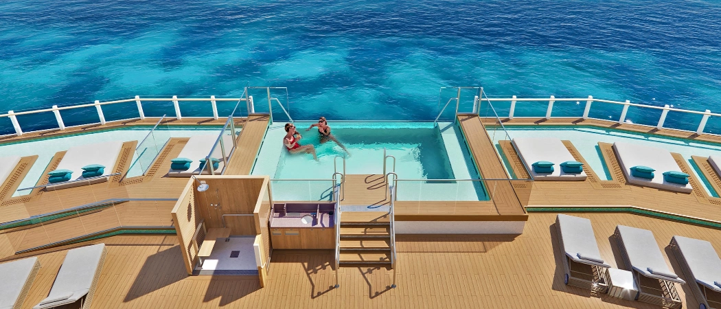 Infinity pool on the deck of a norwegian cruise ship overlooking clear turquoise ocean waters
