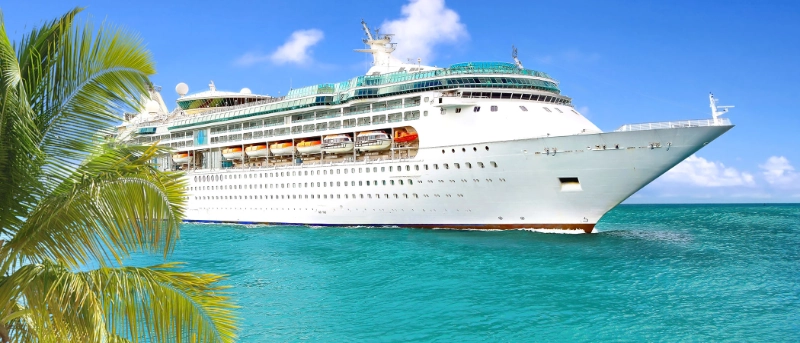 Grand navire de croisière naviguant dans des eaux tropicales turquoise cristallines bordées de palmiers par une journée ensoleillée